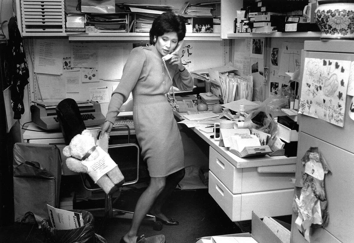 WENDY TOKUDA (July 31, 1990) The anchor works during a busy day at KPIX. According to the photo caption, she's returning calls, and the bear is from a young fan. Note the children's artwork on her filing cabinet.