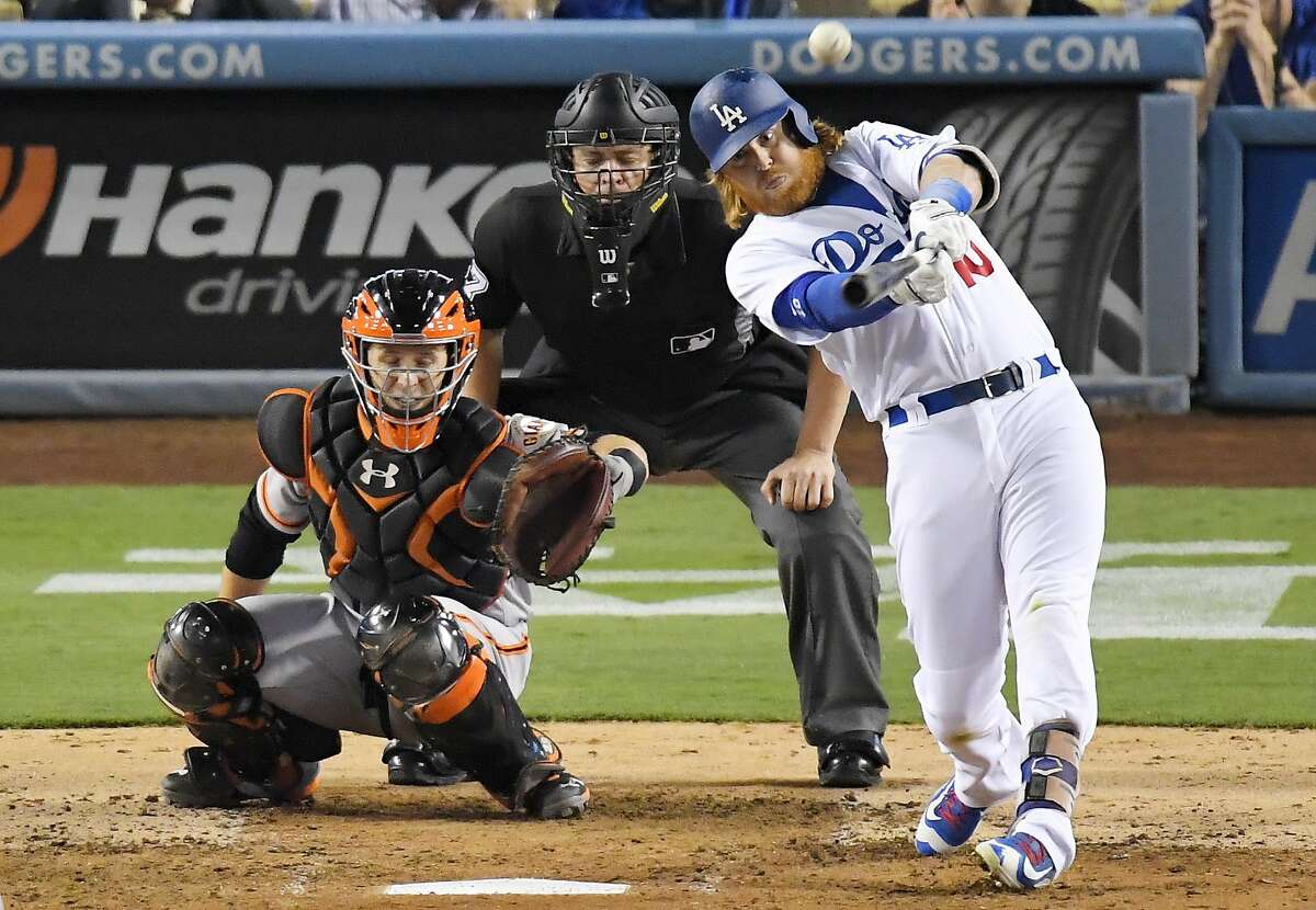 Los Angeles Dodgers' Justin Turner hits a solo home run as San Francisco Giants catcher Buster Posey, left, watches along with home plate umpire Carlos Torres during the fourth inning of a baseball game, Wednesday, Aug. 24, 2016, in Los Angeles. (AP Photo/Mark J. Terrill)