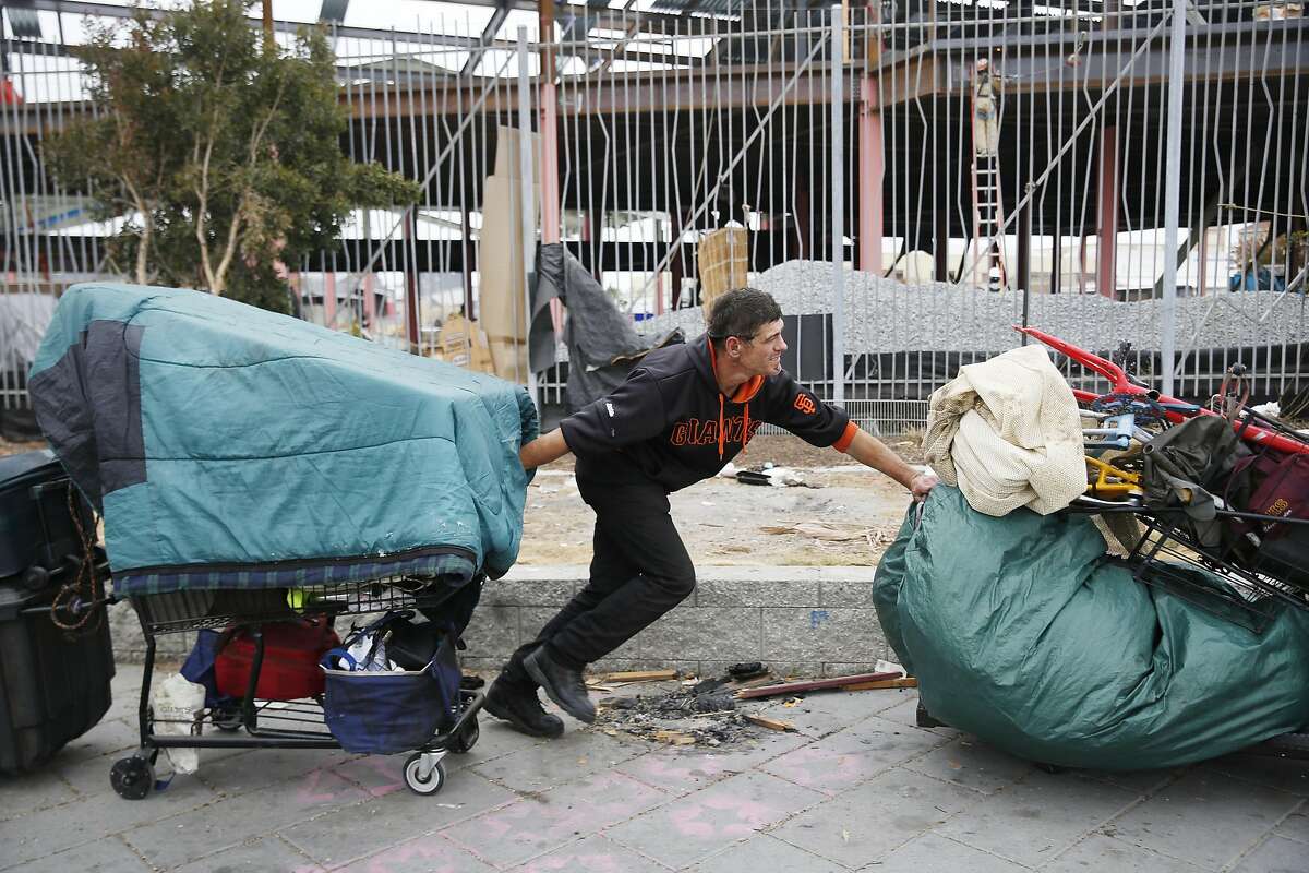 Joaquin Tellez, who says he has been dealing with homelessness off and on since 2000, pushes one cart while pulling another filled with his belongings at the Islais Creek homeless encampment as it is cleared on Monday, August 29, 2016 in San Francisco, California.