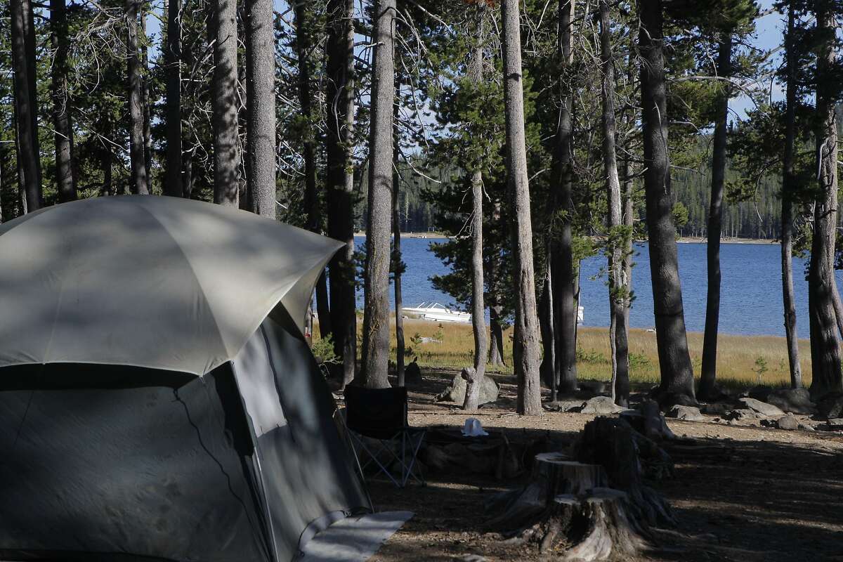 Distant Medicine Lake in Modoc National Forest, with lake-view campsite with boat pulled along nearby shore of Medicine Lake, within short walking distance for campers, is an example of a campground with space available because of the long drive required to get there.
