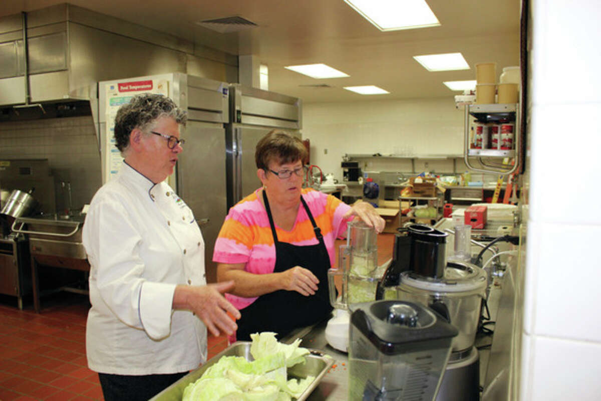 Chef Monique Hooker gives some tips as Laker food service employee Janet Paxton uses a food processor to chop cabbage for a recipe. (Submitted Photo)