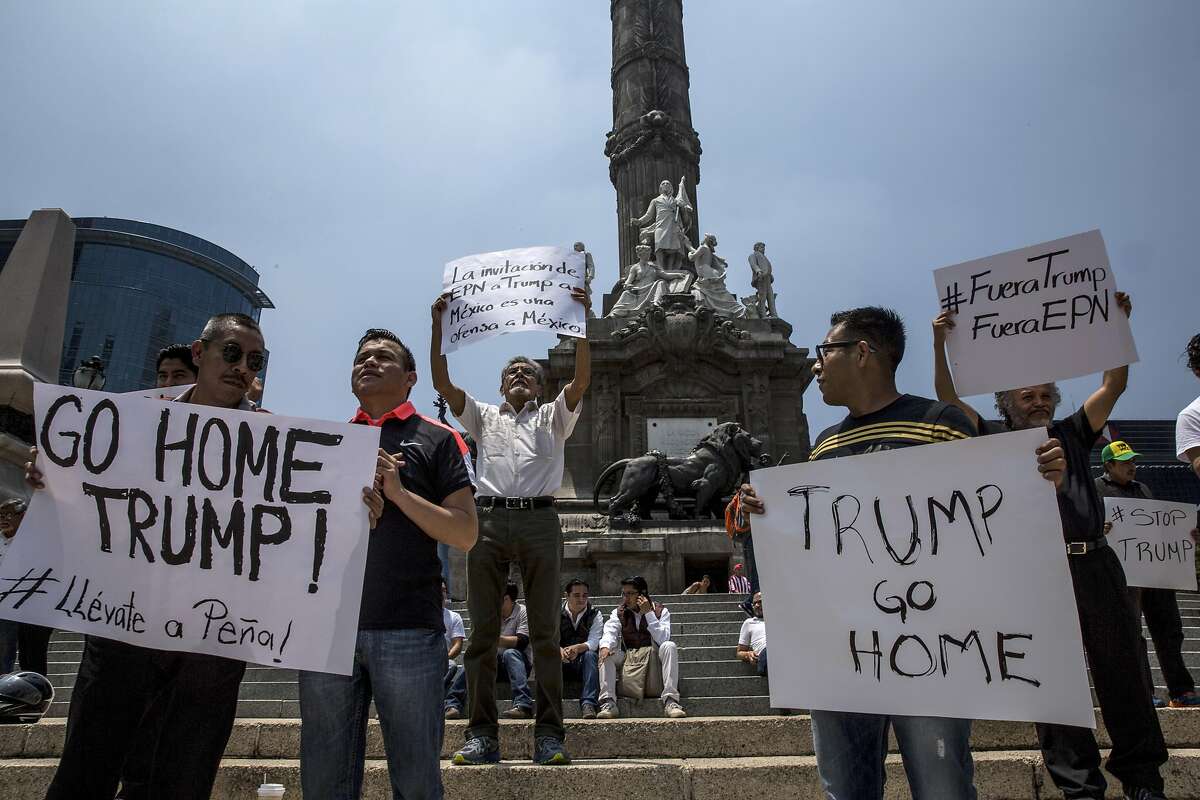 Demonstrators holds signs at the Angel of Independence monument in downtown Mexico City as Donald Trump traveled there, Aug. 31, 2016. President Enrique Pena Nieto is being criticized by many Mexicans for his willingness to meet with Trump, the Republican presidential candidate who has made hostility to immigration a central plank of his campaign. (Adriana Zehbrauskas/The New York Times)