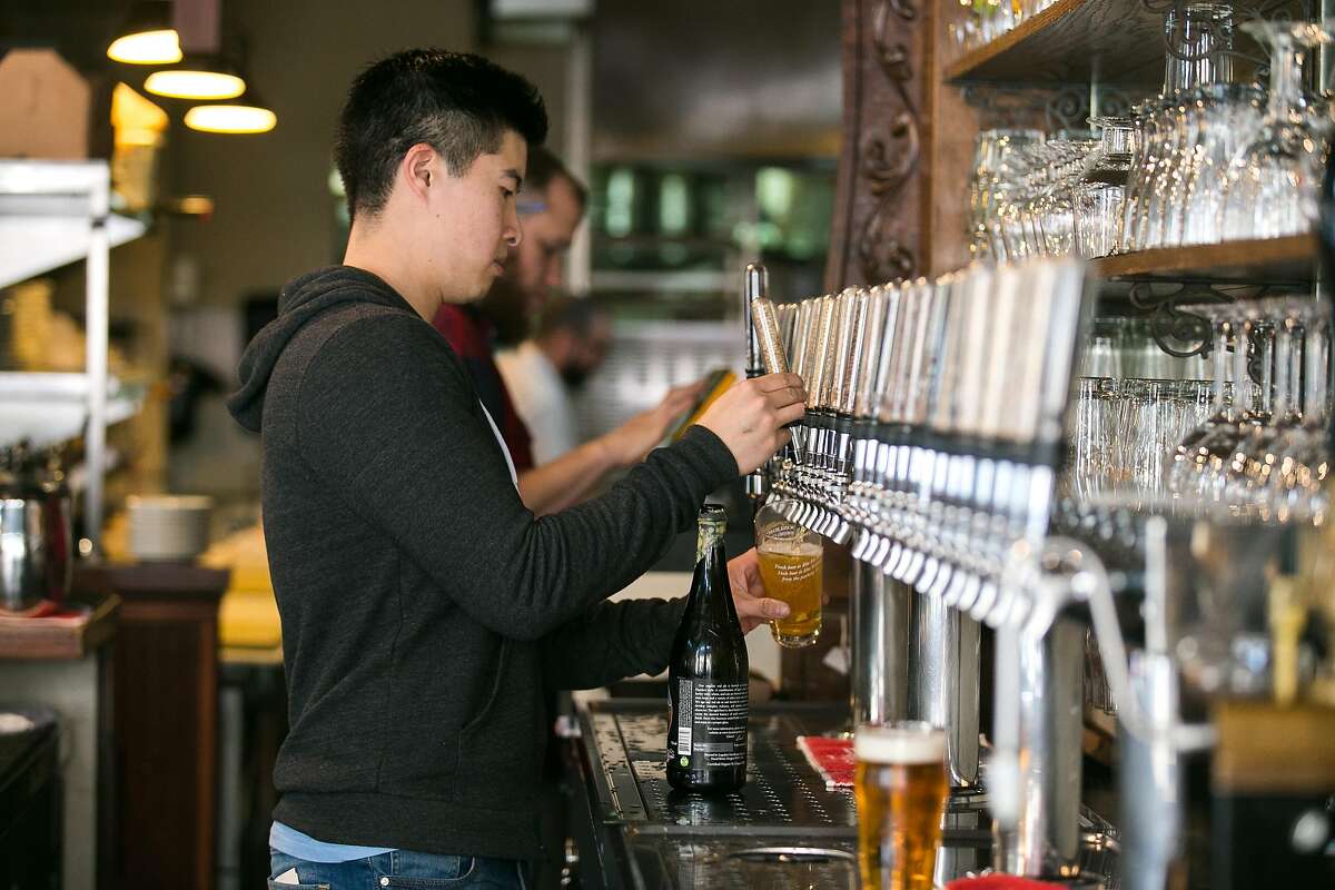 Monk's Kettle's general manager, Xian Choy, pours a beer from one of the 28 beers on tap.