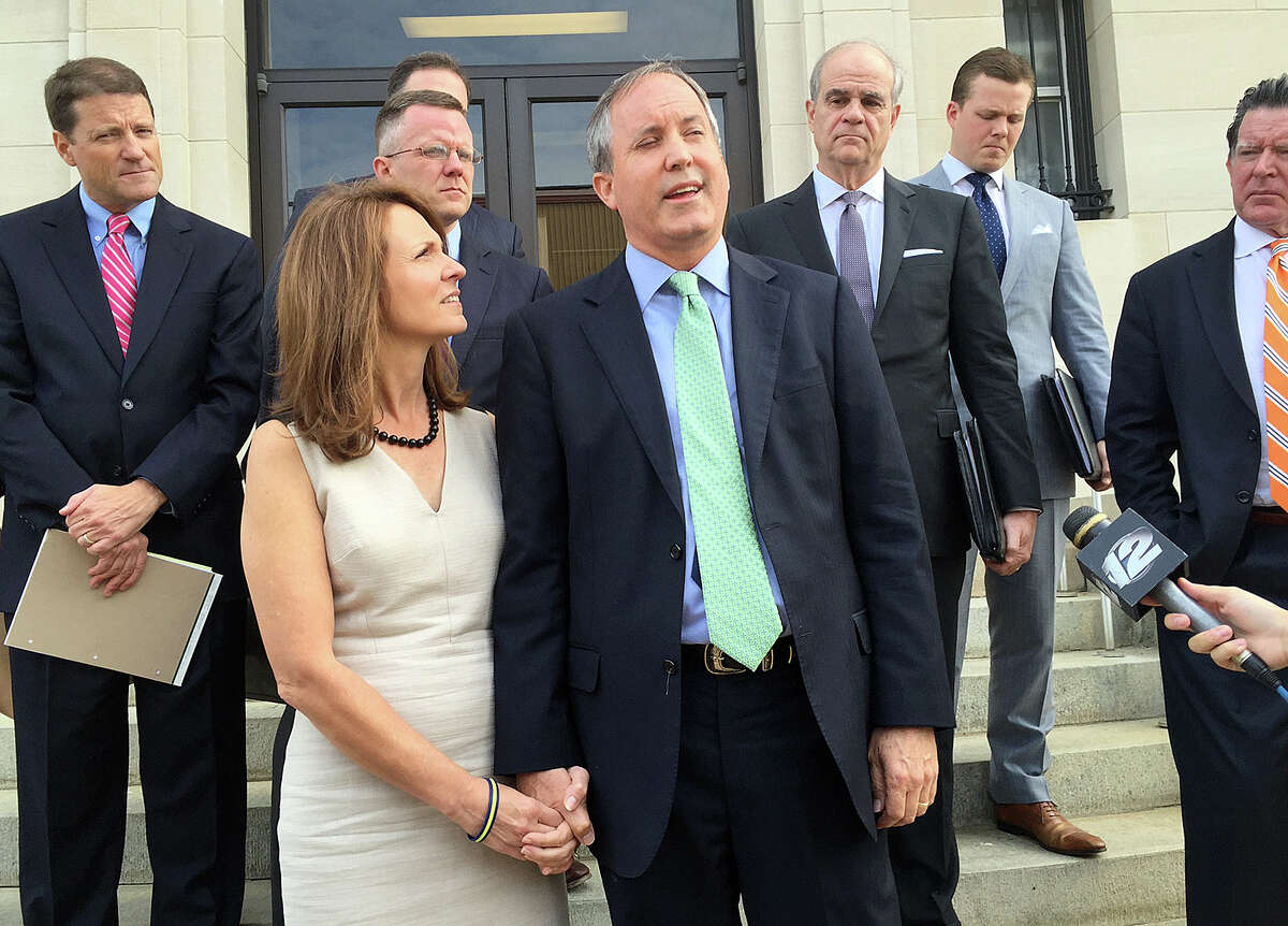 Attorney General Ken Paxton, with his wife Angela, speaks briefly with reporters outside a federal courthouse in Sherman where his attorneys tried to convince a judge to dismiss the civil charges against him.