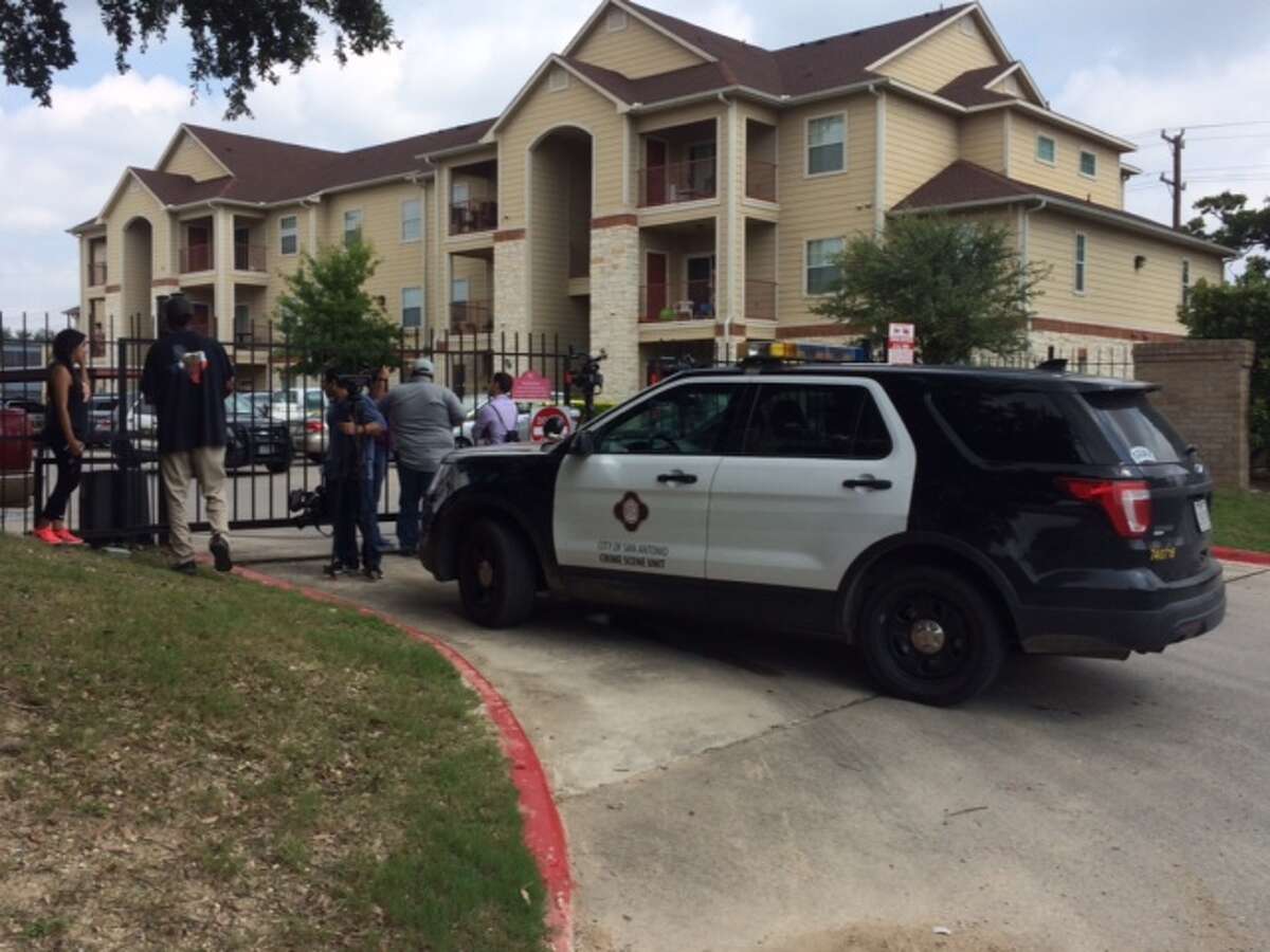 San Antonio police and onlookers gather outside an apartment at 1602 Jackson Keller Road where a 29-year-old mother of three was found stabbed to death Saturday morning.