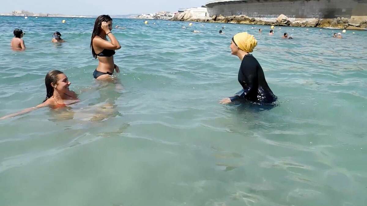 In this image taken from video, Nesrine Kenza who says she is happy to be free to wear a burkini, and two unidentified friends wade into the sea, in Marseille, France, Monday Aug. 29, 2016. A high court struck down the previous ban of the wearing of so called burkini Friday, but the debate revealed raw tensions between the secular establishment and sectors of France's estimated 5 million Muslims. (AP Photo)