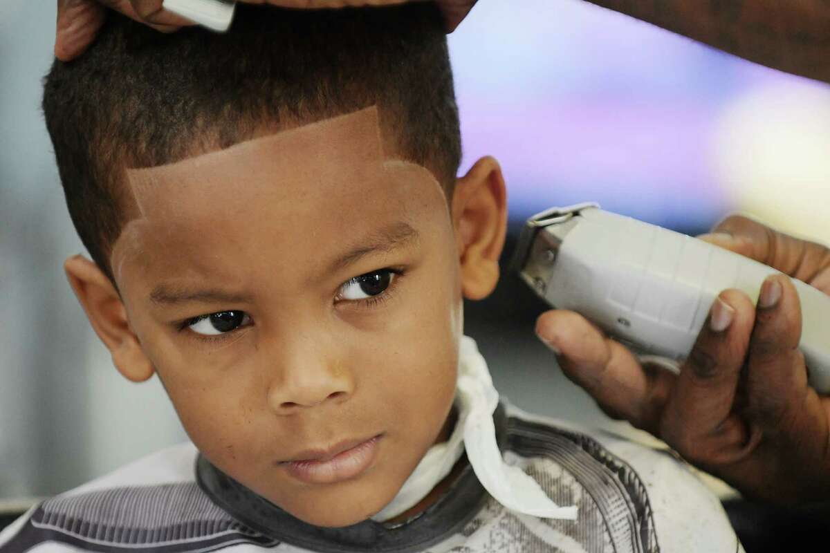 Kenzo Abdul-Aziz, 5, of Rotterdam gets a haircut at Cuts and Blends Barbershop during the 9th Annual Community Cuts event on Sunday, Sept. 4, 2016, in Schenectady, N.Y. The Capital District Chapter of the National Pan-Hellenic Council along with New York State United Teachers, Renaissance Albany Hotel and Vanderheyden hosted the event. Each year the event gives free haircuts or styles to between 300 and 500 children. Four barbershops and two beauty salons took part in the event this year. Chris Ellis, Pan-Hellenic Council event coordinator and past president of the council said that the event is a way to give kids more confidence and encouragement and to help families with the added expenses of going back to school. "We also want to stress to the kids that it is cool to go to school and to do well at school", Ellis said. Along with the haircut children attending the event were given a book and some school supplies. Cuts and Blends has been in business in Schenectady for the past 18 years. (Paul Buckowski / Times Union)
