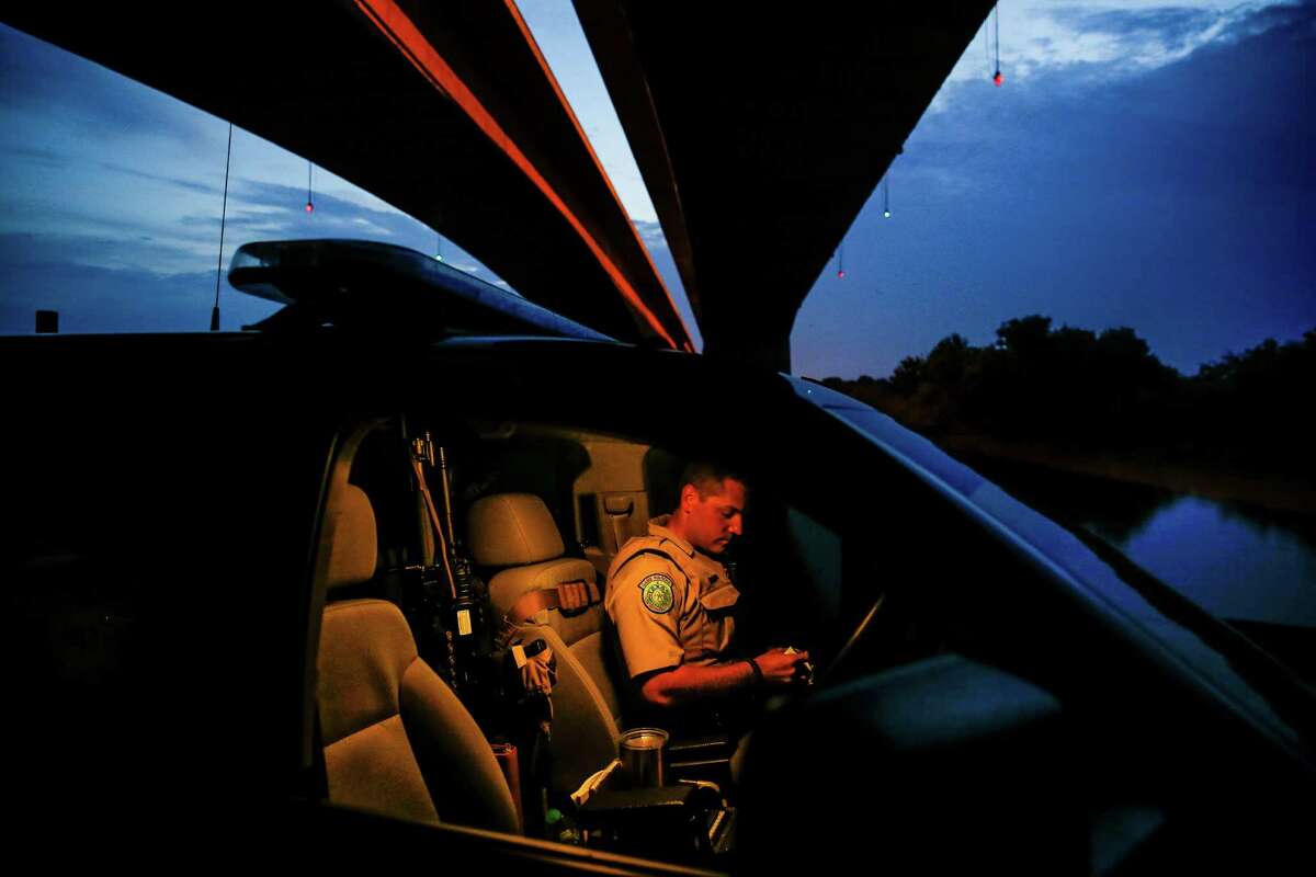 Texas Game Warden Dustin Dockery returns to his truck to look up information after talking to two men fishing along the Trinity River Friday, August 26, 2016 near Wallisville. One of the men didn't have a fishing license and the other, who admitted to driving to the river, had a suspended drivers license. Dockery made the men stop fishing and find a ride home.