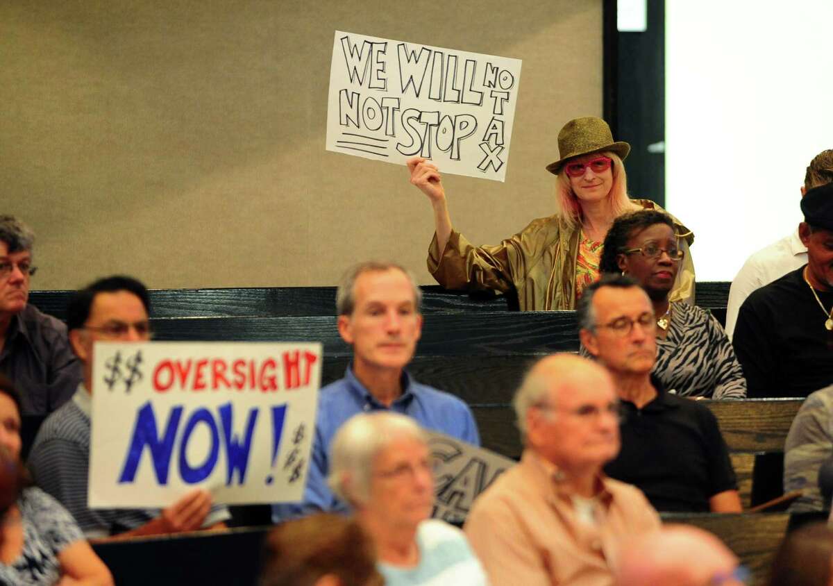 Resident and artist kHyal, in back row, holds up a sign to protest increased taxes during the public comment portion of the Bridgeport City Council meeting at City Hall in Bridgeport, Conn., on Tuesday Sept. 6, 2016. The organization Citizens Working for a Better Bridgeport spearheaded a protest against high taxes and other issues during the gathering, with about two dozen members in attendance.