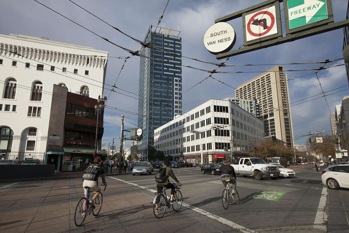Bicyclists ride down Market Street, Saturday, Nov. 21, 2015, in San Francisco, Calif. The city has agreed to sell lots near Market Street and Van Ness Avenue to a housing developer, the latest in a series of large housing projects planned for the area. The cafe building on the left and 30 Van Ness Avenue on the right will be sold.