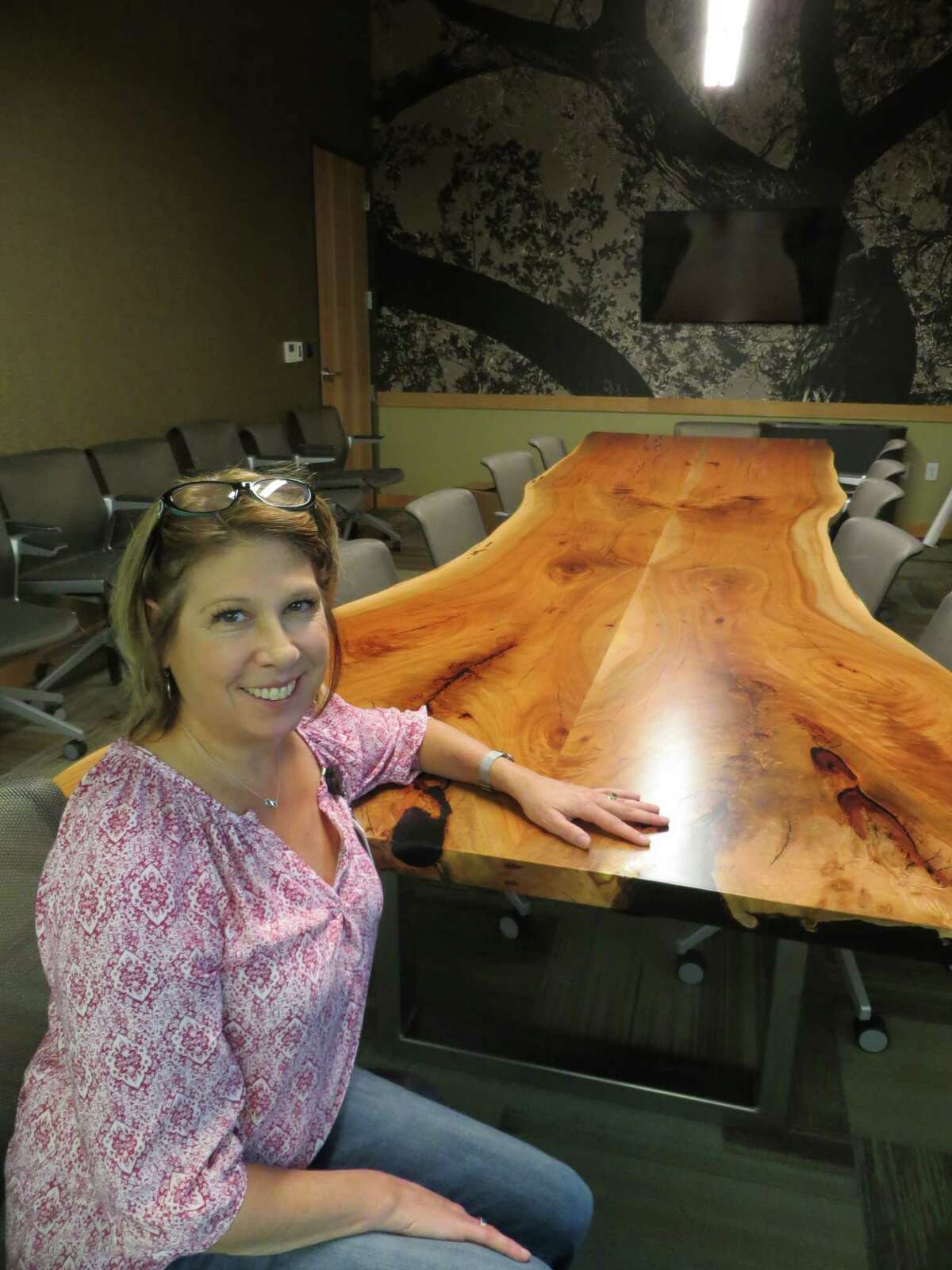 Pecan trees harvested on the site of the new Seguin Public Library were utilized to create wood paneling for the building's interior and benches and tables like the one shown here with Library Director Jacki Gross.