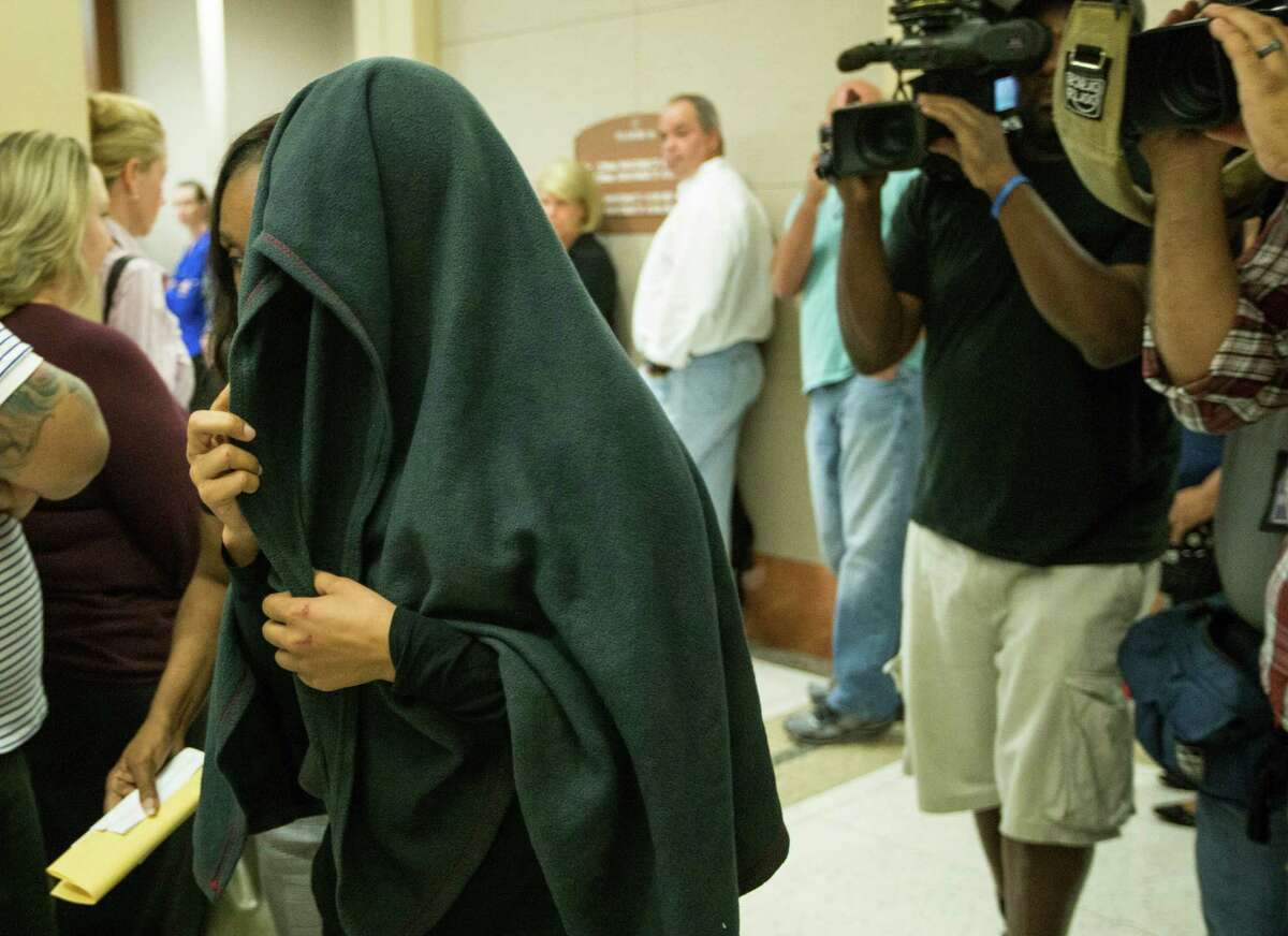 Tuwanna Moore, who is accused of driving drunk and injuring a state trooper,﻿ covers her head as she walks out of a Houston ﻿courtroom ﻿on Wednesday.﻿