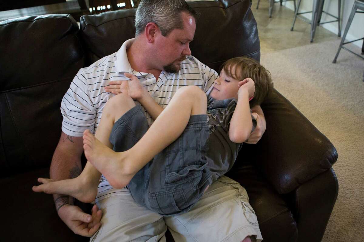 Roanin Walker, 7, lies down on the lap of his father Trevor Walker while they negotiate privileges, Saturday, July 23, 2016, in Kingwood.
