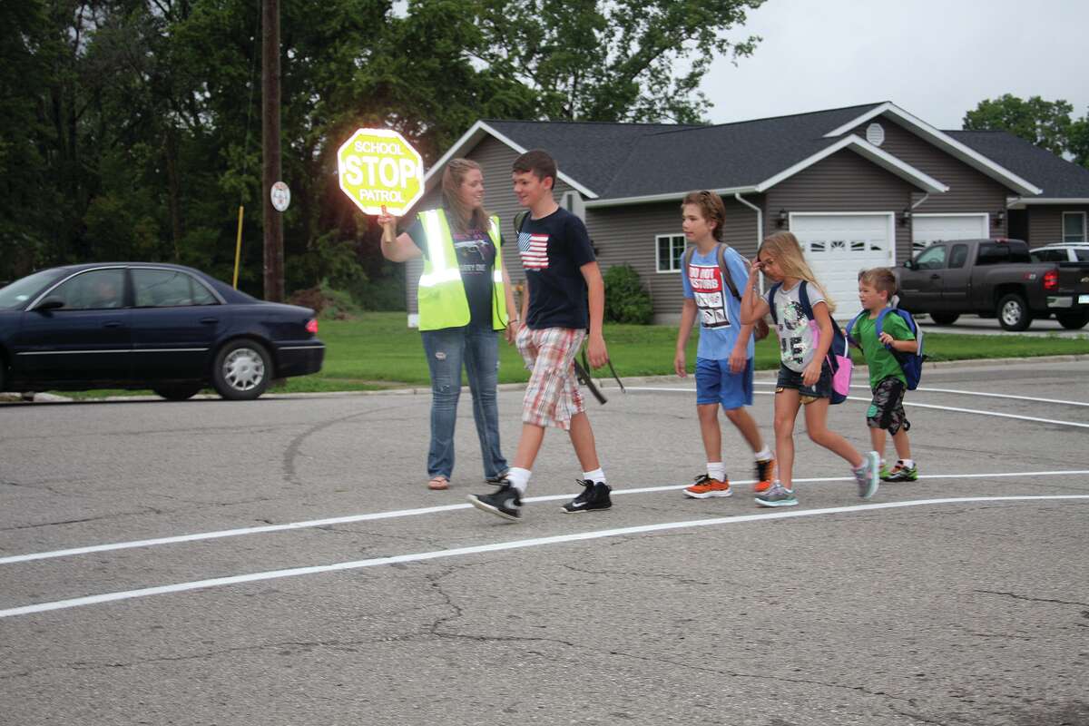   Casey Armitage of Harbor Beach stops traffic Thursday for school students. She used to carry a pistol on the job until recent action by the city council.