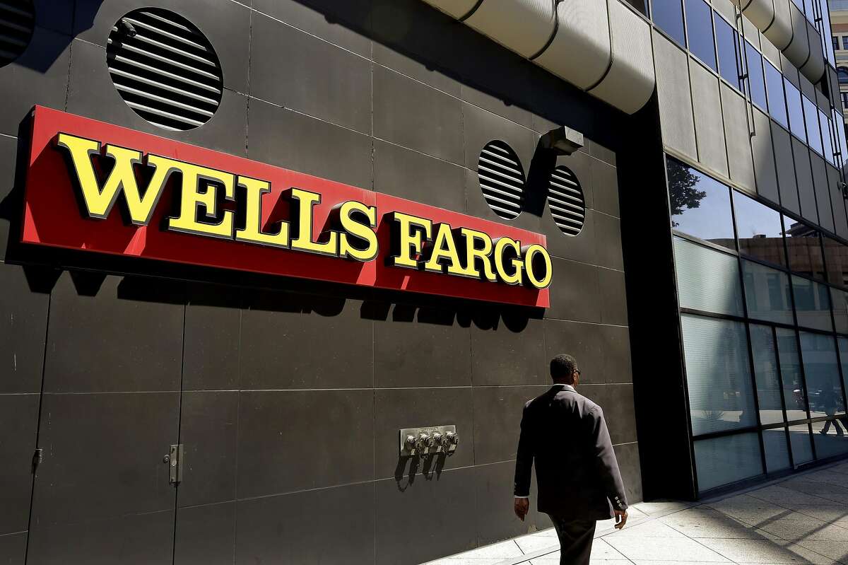 FILE - In this July 14, 2014, file photo, a man passes by a Wells Fargo bank office in Oakland, Calif. Regulators announced Thursday, Sept. 8, 2016, that Wells Fargo is being fined $185 million for illegally opening millions of unauthorized accounts for their customers in order to meet aggressive sales goals. (AP Photo/Ben Margot, File)
