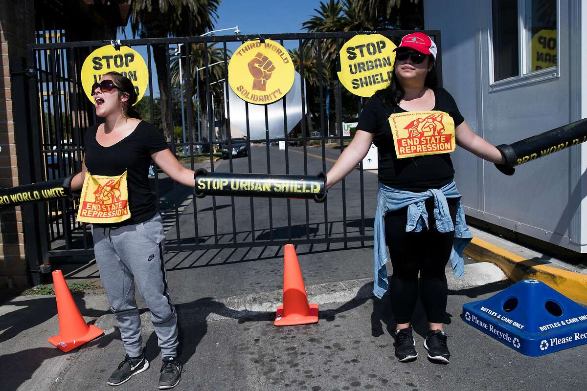 Megan Whelan, left, and Natalie Tran, of Oakland, stand with their arms linked at the main entrance outside the Alameda County Fairgrounds in protest of Urban Shield 2016 in Pleasanton, Calif. on Friday, Sept. 9, 2016.