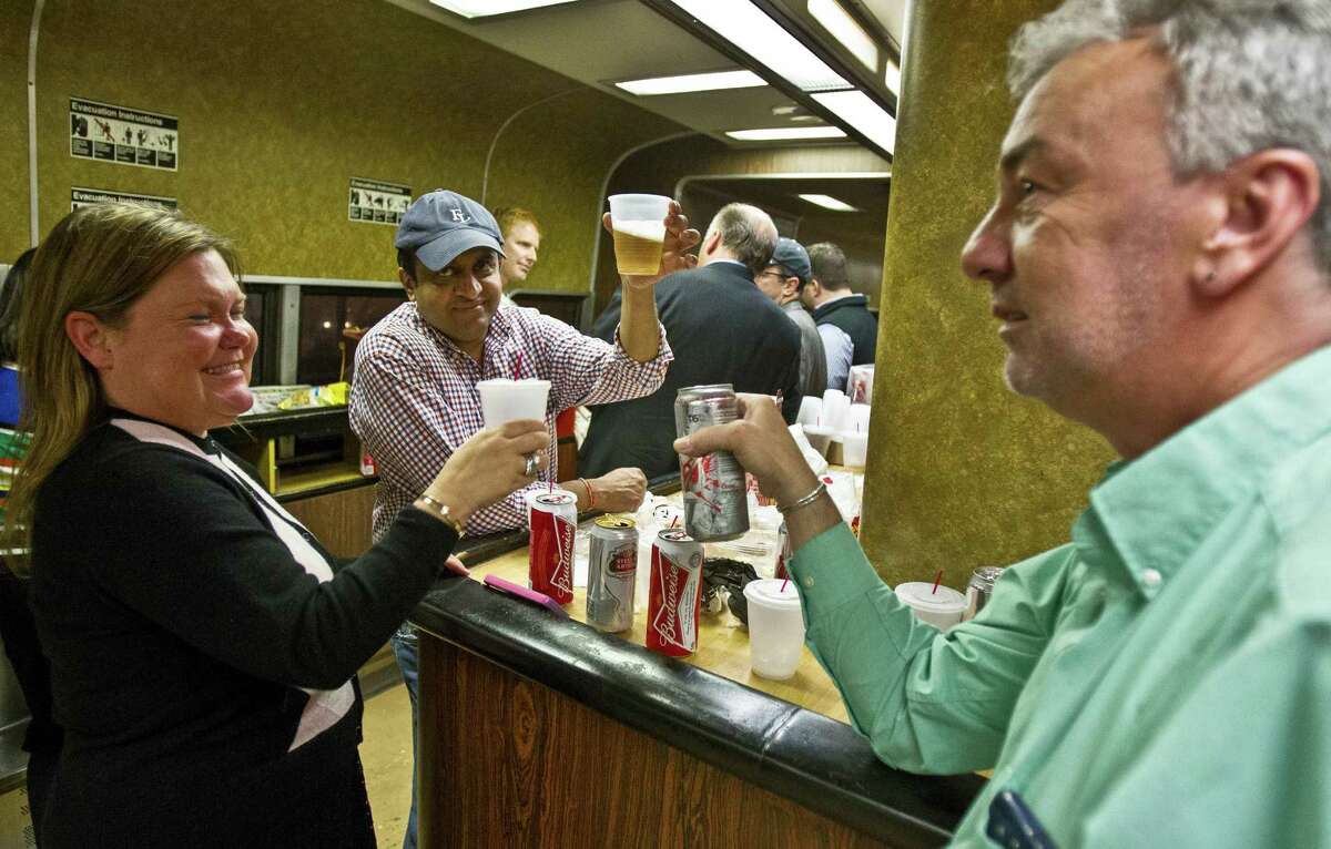 Nan Buziak Lexow, left, Srikanth Reddy, center, and Mark DeMonte, right, raise a toast while riding the bar car on the 7:07 p.m. train from Grand Central Terminal in New York to New Haven, Conn., Thursday, May 8, 2014. The trio toasted the bar car, being retired from Metro-North's New Haven Line after Friday's afternoon rush hour. The cars were a fixture on Metro-North Railroad trains for at least a half century. The cars, decked out with orange walls and faux wood paneling, are being retired Friday, because they cannot be coupled to the new fleet of train cars on the New Haven line. (AP Photo/Michael R. Sisak)