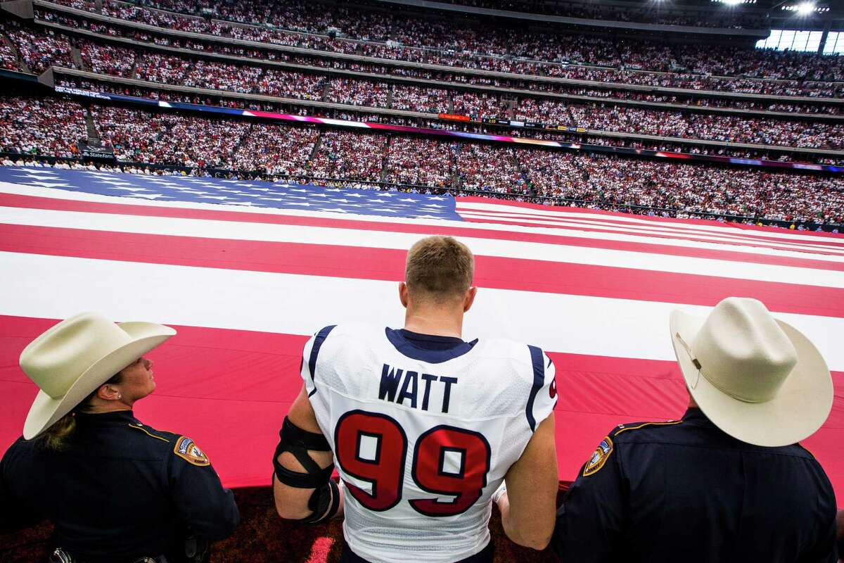 Houston Texans defensive end J.J. Watt (99) holds a giant american flag with first responders during the national anthem before the first quarter of an NFL football game at NRG Stadium on Sunday, Sept. 11, 2016, in Houston.