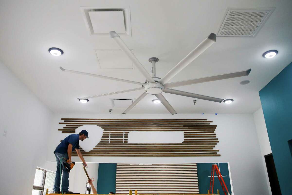 TCR Building Group project manager Jason Long hangs wood pieces for a sign as Big Ass Fans prepares to open its first showroom store Monday, September 12, 2016 in Houston. ( Michael Ciaglo / Houston Chronicle )