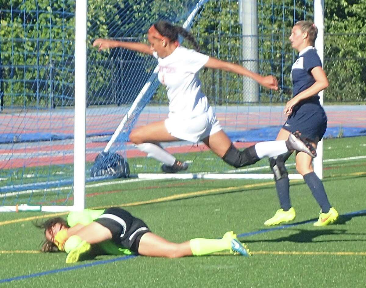 Danbury's Sara DaSilva leaps over Staples goalkeeper Anna Sivinski after Sivinski came sliding out to take the ball away during their soccer game at Danbury High School Sept. 12, 2016. Staples defender Erin McGroarty trails the play.