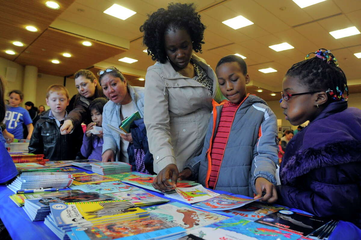 Marcelle Dawson helps her son Alexander pick out a book during the Stamford Public Education Foundation bi-annual Reading is Fundamental Book Give-A-Way at the Ferguson Library. The education foundation is celebrating its 20th anniversary this year.