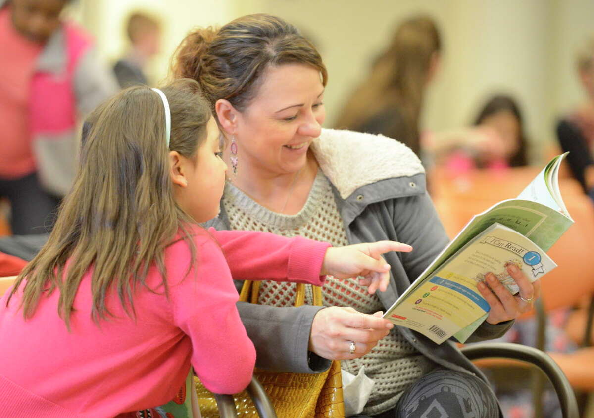 Lina Quintero, of Stamford, reads a book to her daughter Sofia, 6, during the Stamford Public Education Foundation bi-annual Reading is Fundamental Book Give-A-Way at the Ferguson Library. The foundation is celebrating its 20th anniversary this year.