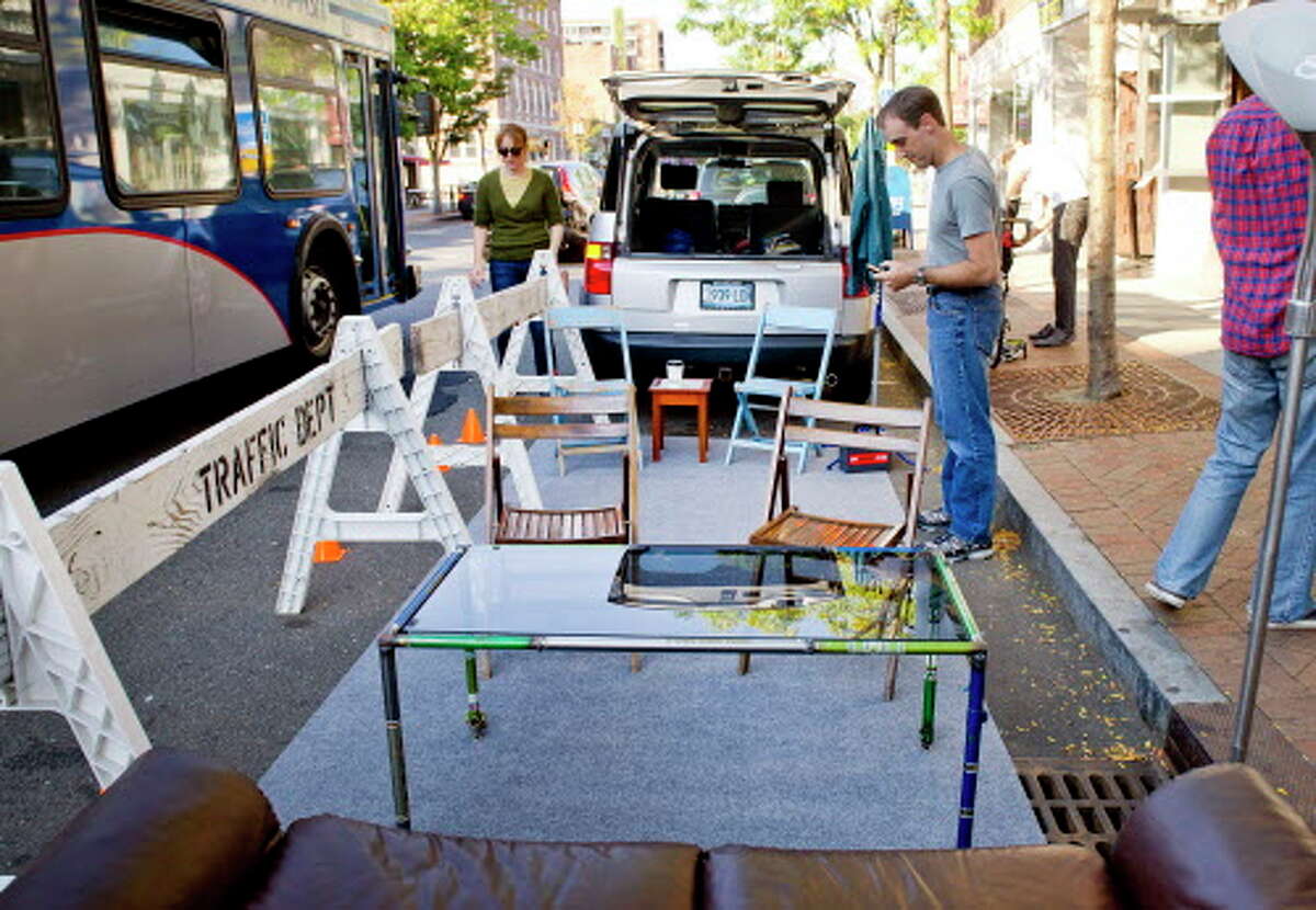 Mike Norris, right, and Emily Provonsha, left, help set up a parklet in front of Lorca on Bedford Street in Stamford, Conn., on Friday, September 19, 2014. The parklet it set up in a parking space and is intended to encourage people to think about how best to use public space.