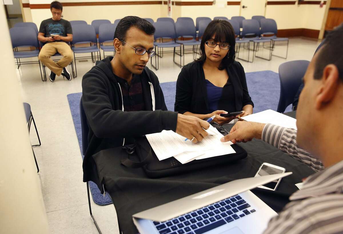 Omar Masry, Senior Administrative Analyst, right, helps Mehul Dhorda, left, and his wife Arpita Patel with registering their short term rental during a public information workshop held by San Francisco's Office of Short-Rent Rentals for vacation-rental hosts to learn about their registration requirement with the city in the Presidio Branch Library June 28, 2016 in San Francisco, Calif.