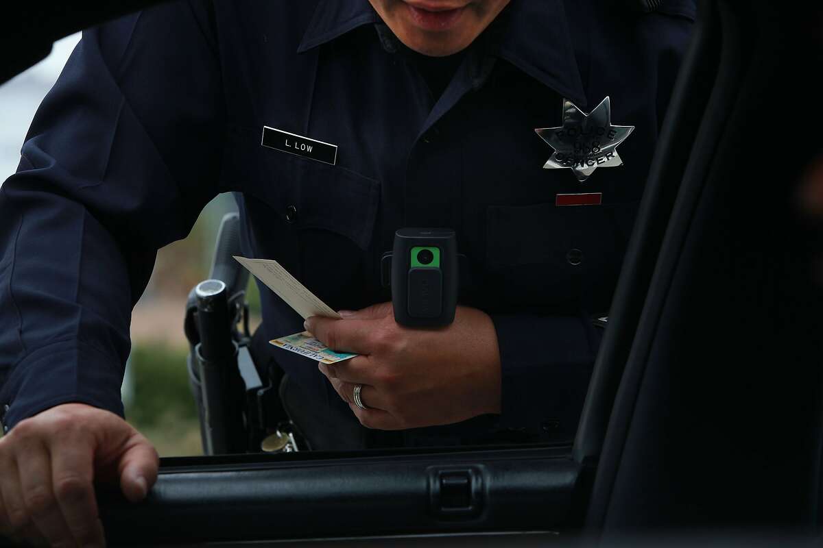 Oakland officer Lawrence Low issuing a ticket as he has his new wearable video camera clipped to his uniform (green square) as he stops someone for expired license plates in Oakland, Calif., on Wednesday, September 15, 2010.
