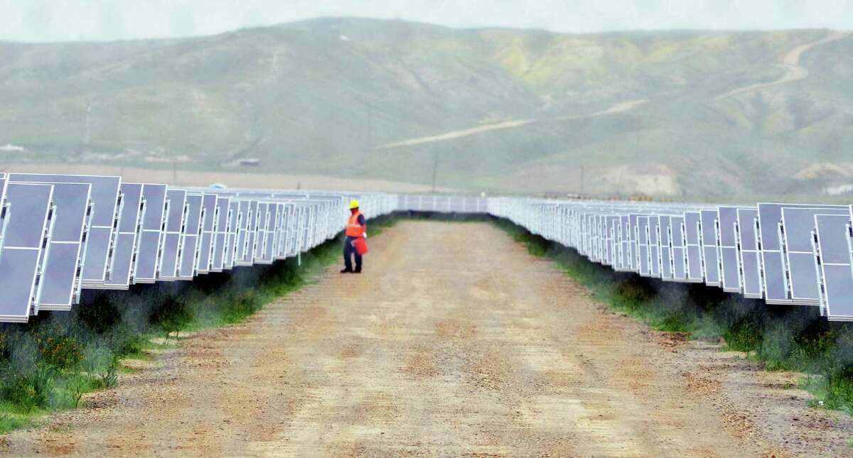 FILE - In this Tuesday, Aug. 3, 2011 file photo, a worker looks over solar panels at the NRG Solar and Eurus Energy America Corp.Â?’s 45-megawatt solar farm in Avenal, Calif. Energy companies are wrapping renewable energy projects and other power-related assets that generate steady cash into new companies they hope attract investors hunting for dividends. (AP Photo/The Sentinel, Apolinar Fonseca, File)