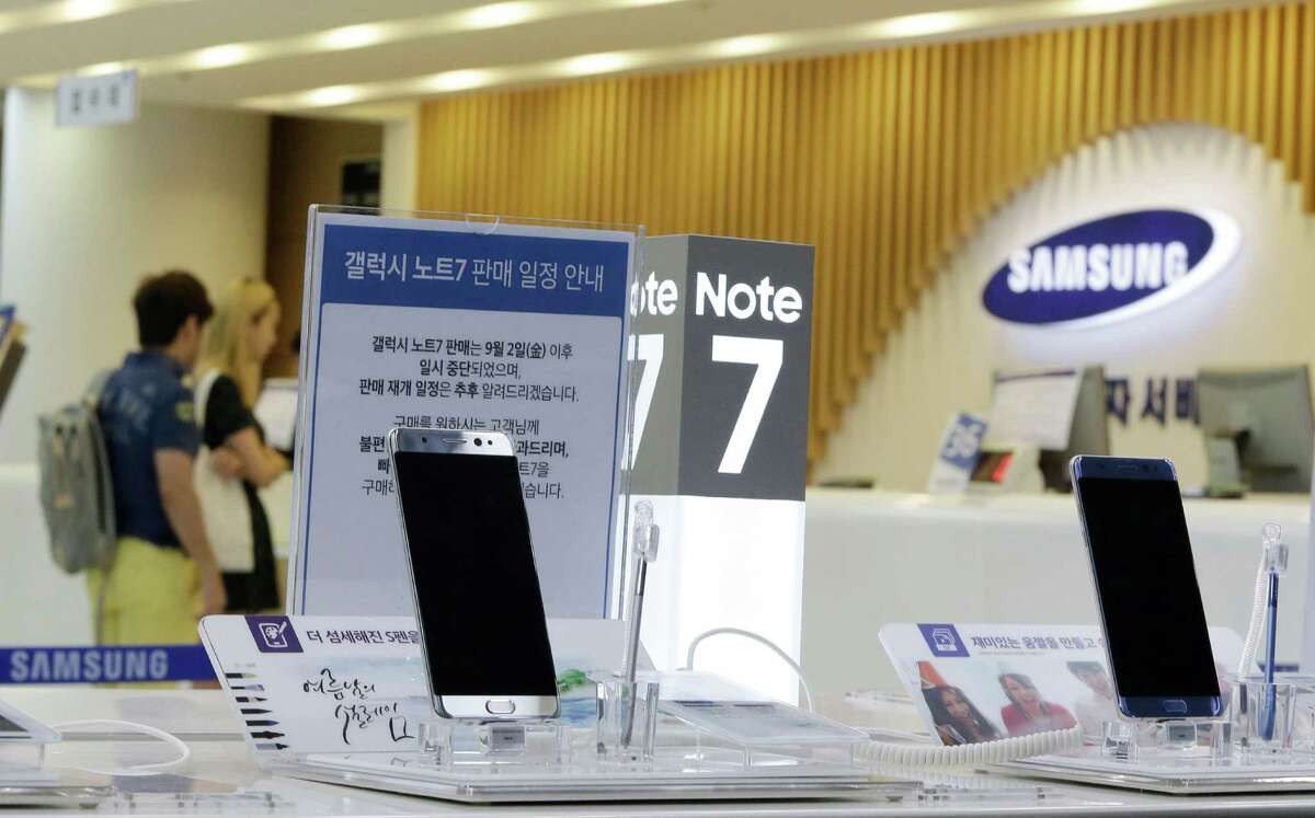 FILE - In this Sunday, Sept. 11, 2016 file photo, customers wait for recall of their Samsung Electronics Galaxy Note 7 smartphones as powered-off Galaxy Note 7 smartphones are displayed at the company's service center in Seoul, South Korea. Samsung on Tuesday, Sept. 13, 2016, plans to issue a software update for its recalled Galaxy Note 7 smartphones that will prevent them from overheating by limiting battery recharges to under 60 percent. (AP Photo/Ahn Young-joon, File)