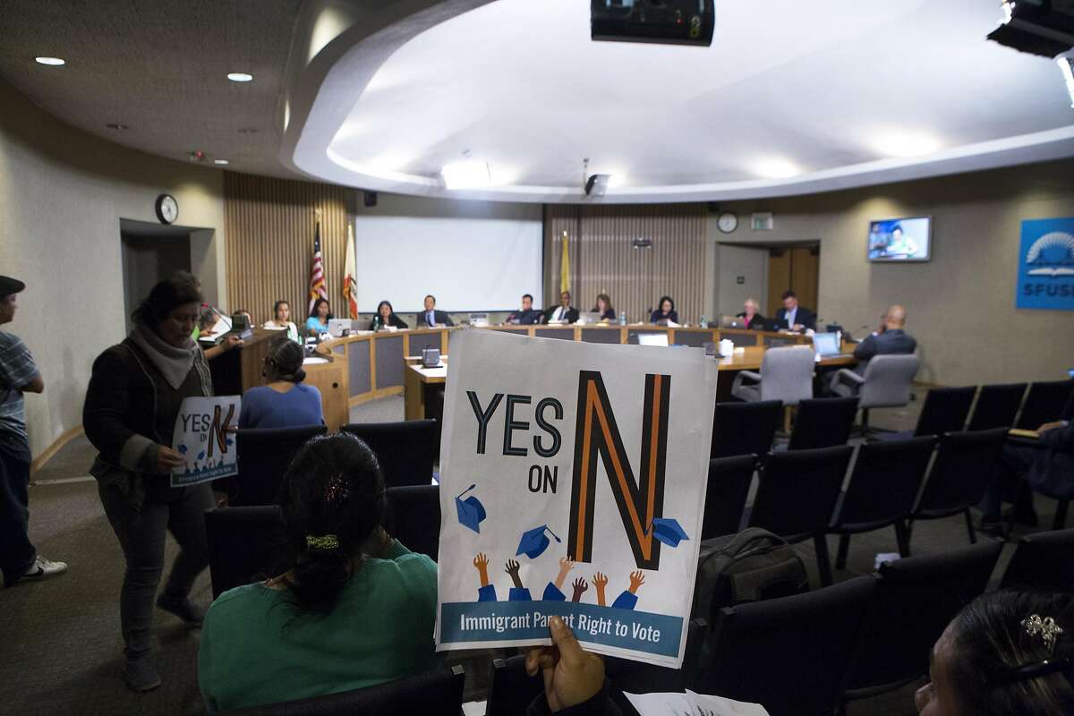 Diana Vasquez, center, holds a sign up in the air, as she listens to public comment, during an SFUSD meeting, on Tuesday, Sept. 13, 2016 in San Francisco, Calif. The school board passed a decision to support Prop N, which, if passed by voters later this year, would authorize S.F. residents, who are not U.S. citizens, but have children who attend S.F. schools, to vote in elections for the Board of Education. Vasquez is a mother of two children who attend S.F. schools.