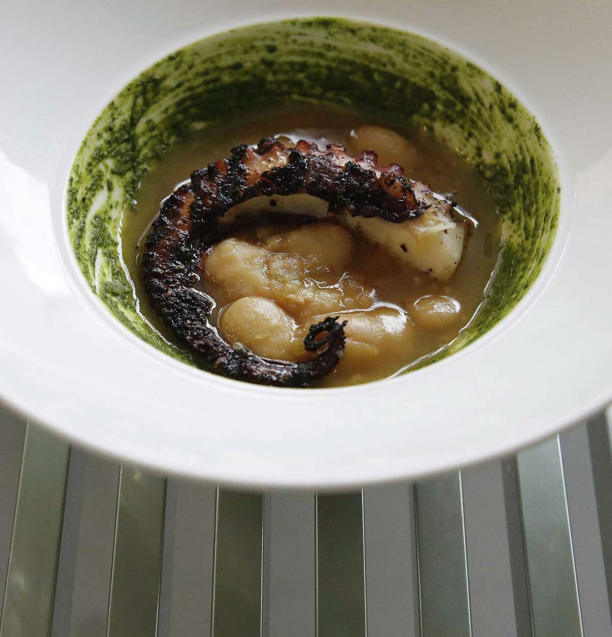 Char-grilled Spanish Octopus with braised corona beans and a basil pistou at Rebelle
