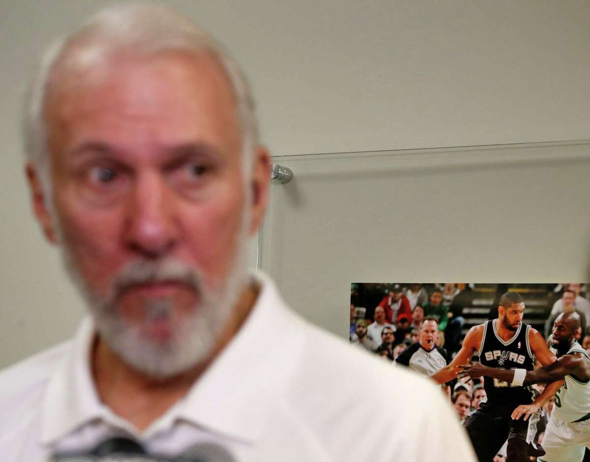 Spurs head coach Gregg Popovich addresses the media on May l3, 2016, at team facility, with focus on a Tim Duncan photo in the background.