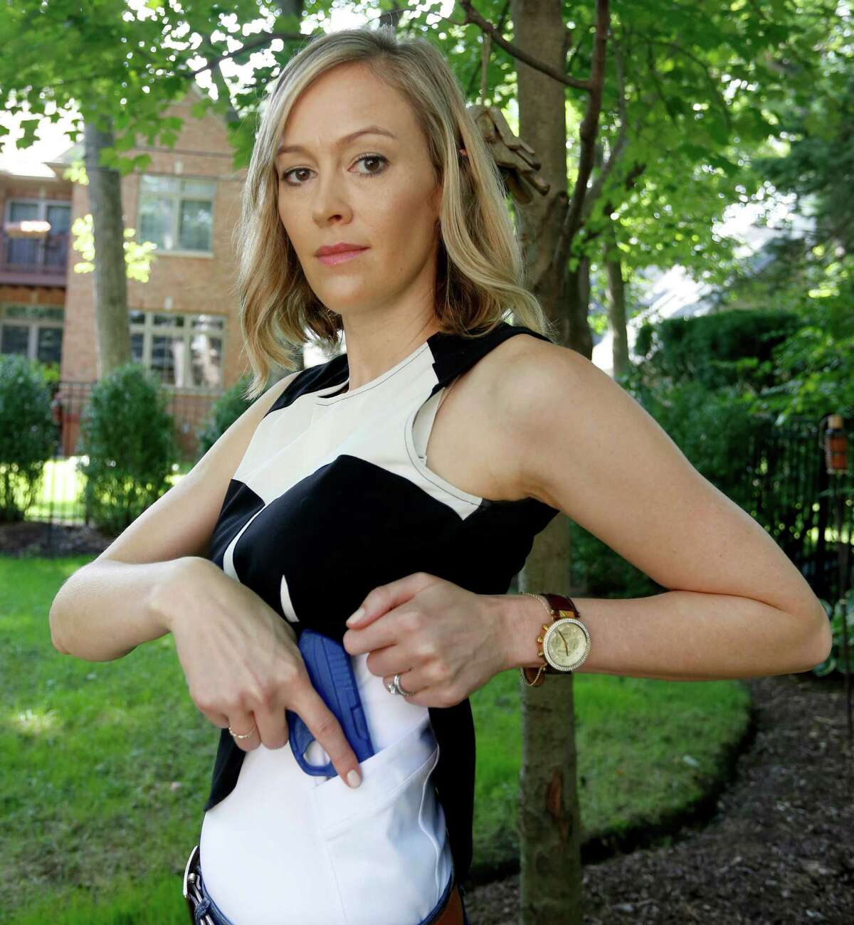 In this Aug. 29, 2016 photo, Marilyn Smolenski uses a mock gun to demonstrate how to pull a handgun out of an undergarment she designs for concealed carry at her home in Park Ridge, Ill. Interest in clothing that allow women to carry a firearm concealed is rising. Pioneers in the industry say they allow women to avoid looking frumpy and still carry a firearm safely and effectively. (AP Photo/Tae-Gyun Kim)