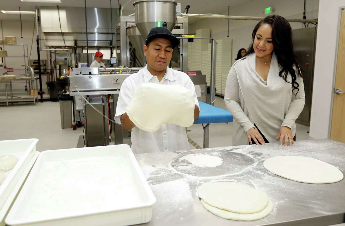 In this Monday, Aug. 29, 2016 photo, co-founder and CEO, Julia Collins, right, chats with employee Jose Lopez as he makes pizza dough at Zume Pizza in Mountain View, Calif. The startup, which began delivery in April, is using intelligent machines to grab a slice of the multi-billion-dollar pizza delivery market. Zume is one of a growing number of food-tech firms seeking to disrupt the restaurant industry with software and robots that let them cut costs, speed production and improve worker safety. (AP Photo/Marcio Jose Sanchez)