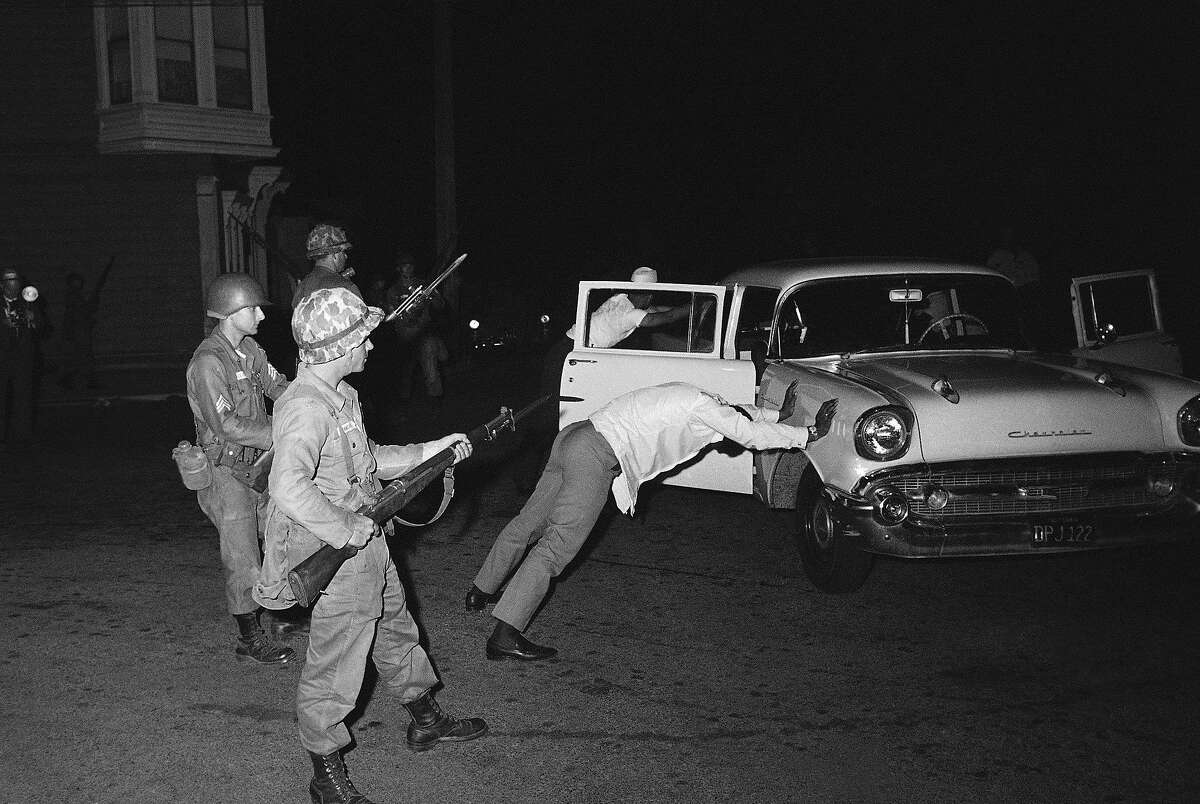 Two black occupants of this car are held at bay by California National Guardsmen with fixed bayonets in the Hunters Point riot area of San Francisco, Sept. 28, 1966. The car was stopped when it was suspected of carrying guns and ammunition. The area was secured by Guardsmen who imposed curfew. (AP Photo/Robert H. Houston)