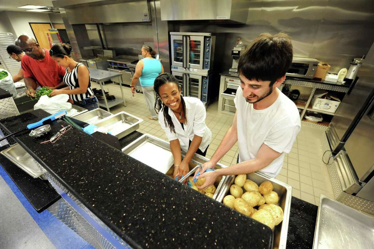 AVillage members Tracian Gordan, center, and Sam Fein, right, have some fun as they wash potatoes in preparation for Mississippi Day on Thursday, Sept. 17, 2015, at Victory Church Dream Center in Albany, N.Y. (Cindy Schultz / Times Union archive)
