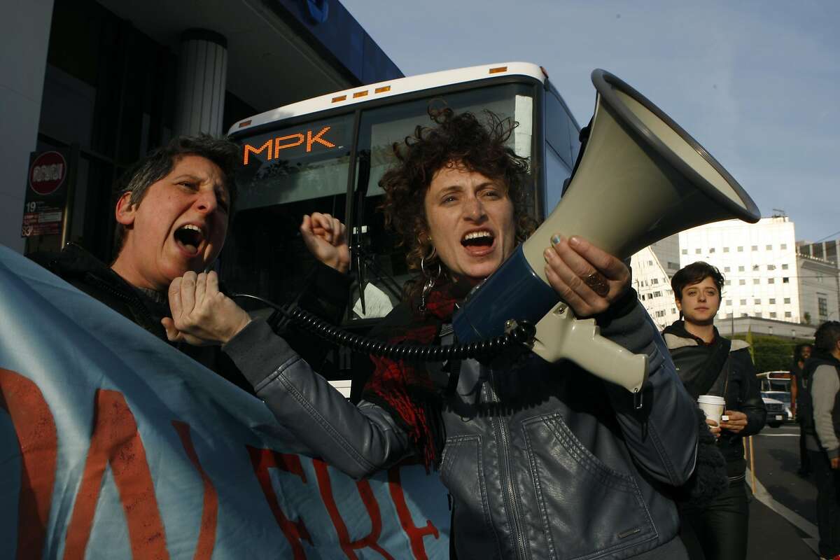 Sara Shortt (left) from the Housing Rights committee of San Francisco and activist Erin McElroy (right) block a Facebook bus heading to Menlo Park on 8th at Market streets in San Francisco, Calif., on Tuesday, January 22, 2014. The San Francisco Metropolitan Transportation Agency votes on an 18-month pilot plan allowing Google buses to use designated Muni bus stops to pick up and drop off tech commuters to Silicon Valley.