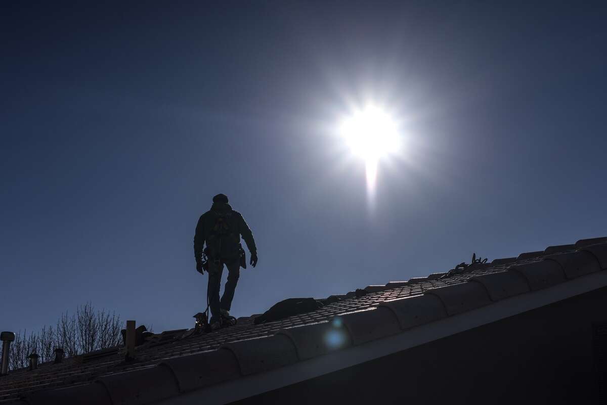 A worker walks on a roof during a SolarCity residential installation in Albuquerque, New Mexico, on Feb. 8, 2016.
