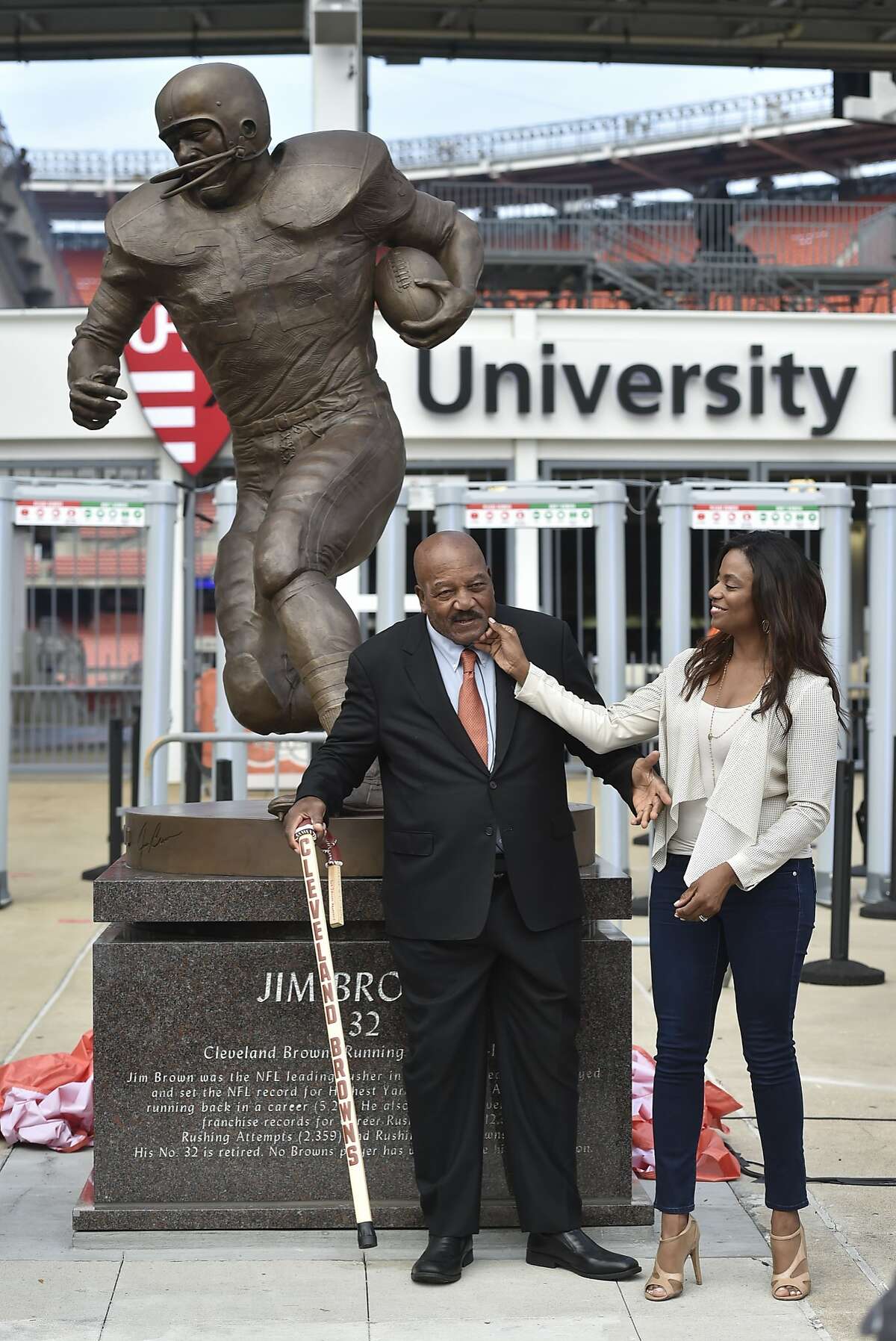 Cleveland Browns Pro Football Hall of Famer Jim Brown, center, and his wife Monique, right, is honored with a ceremony and statue outside FirstEnergy Stadium before an NFL football game against the Baltimore Ravens, Sunday, Sept. 18, 2016, in Cleveland. (AP Photo/David Richard)