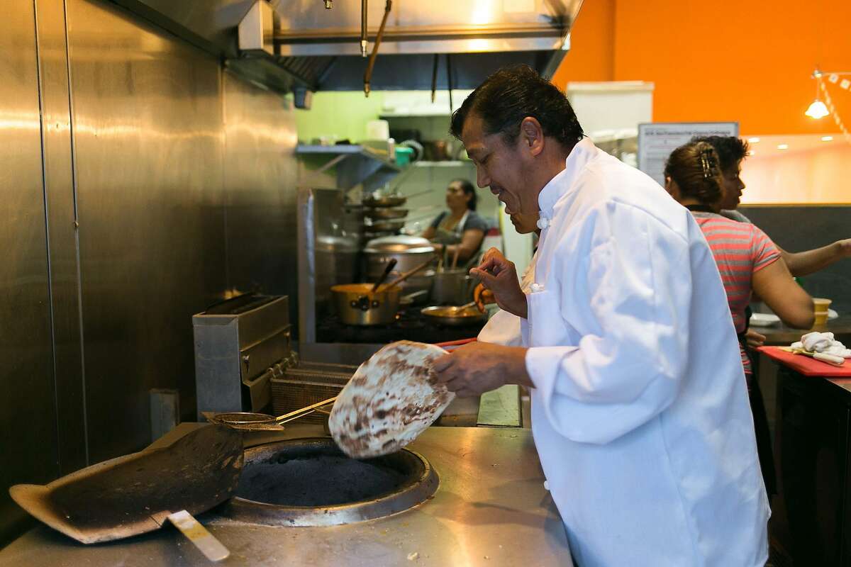 Perm Tamang pulls cooked naan from the oven at Cuisine of Nepal in S.F.