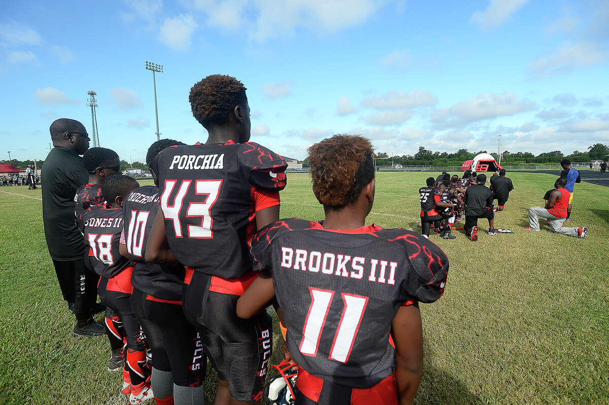 Some members of the Beaumont Bulls youth football team and coaches kneel while others stand during the playing of the National Anthem prior to their home game Saturday. The team has gotten national attention after choosing to kneel in protest of social injustice at their game last week. After receiving numerous negative comments, including threats of violence aimed at both the 11 - 12-year-old players as well as coaches and parents, questions arose as to whether their protest would continue, and what negative actions may be taken by board members of the Bulls football program. Ultimately, no action was immediately taken against those players who chose to kneel, and the game continued as scheduled. Photo taken Saturday, September 17, 2016 Kim Brent/The Enterprise
