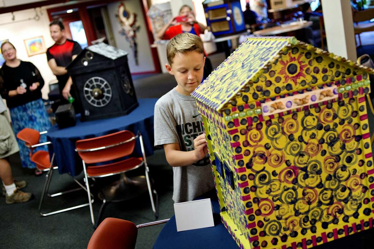 Kellan Galloway, 10, checks out a little library decorated by artist Linda Z. Smith during a thank-you party on Monday at Creative 360 for artists who've decorated 15 Little Free Libraries that Jeff Havens plans to deliver in Midland to over 35 people who have requested a library for their yards. Kellan's family will be one of the private residents displaying a library. Chippewa Nature Center, the Community Center, the Salvation Army, West Midland Family Center, and several others will be receiving them.