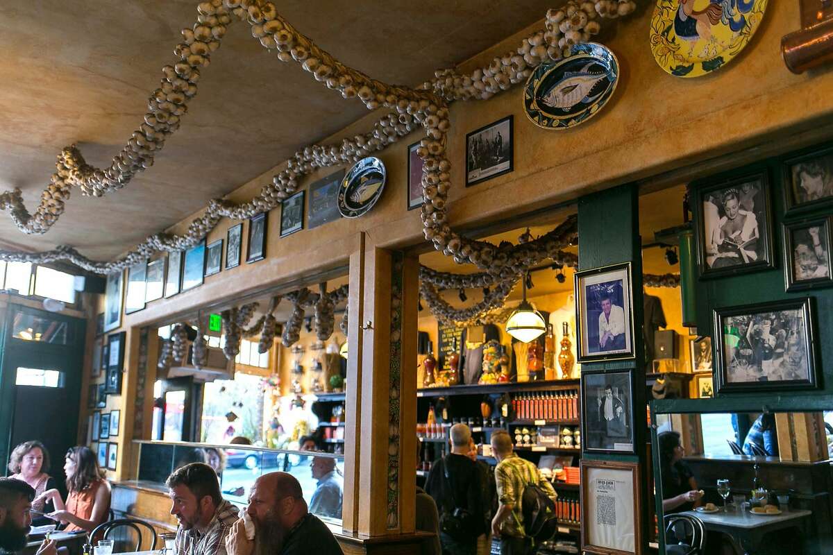 Garlic drapes from the ceiling while photos and decorative plates line the walls at The Stinking Rose in S.F.