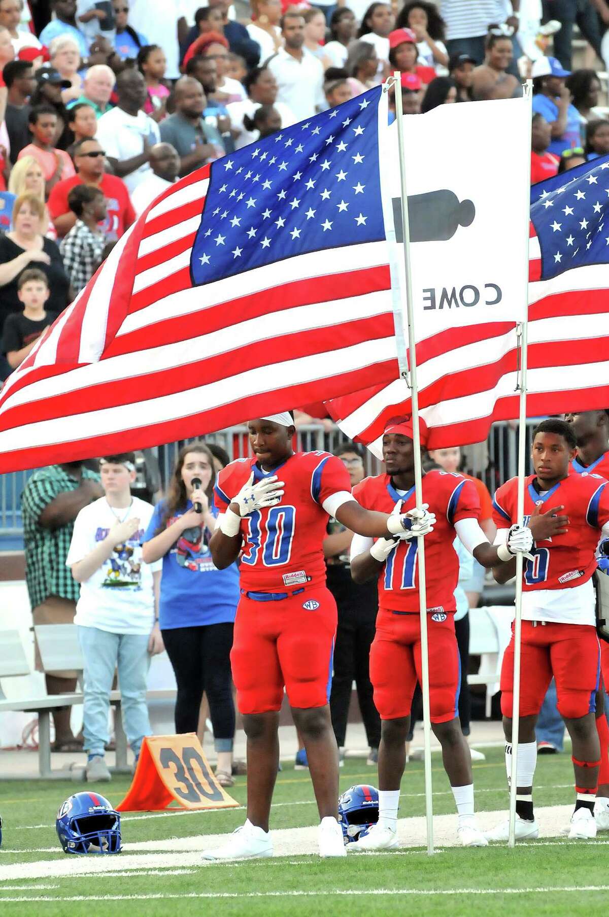 Members of the West Brook Bruins stand on Sept. 2 with their hands over their hearts, as several hold the American Flag as the national anthem is played prior to their Week 2 game against the Ozen Panthers at the Thomas Center in Beaumont. (Mike Tobias/The Enterprise)