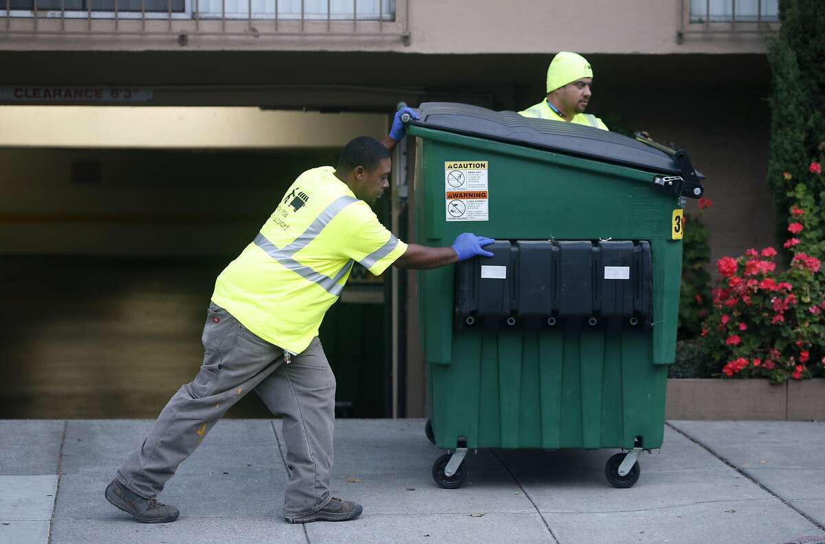 Alvin Hughes III (left) and Junior Fiame push a trash dumpster to the sidewalk in front of a large apartment building on Alice Street before the contracted garbage collector arrives in Oakland, Calif. on Wednesday, Sept. 14, 2016. Bay Area Bin Service provides push-pull service of dumpsters and recycle bins for large residential and commercial clients at a fraction of the cost charged by the contracted garbage collection company Waste Management.