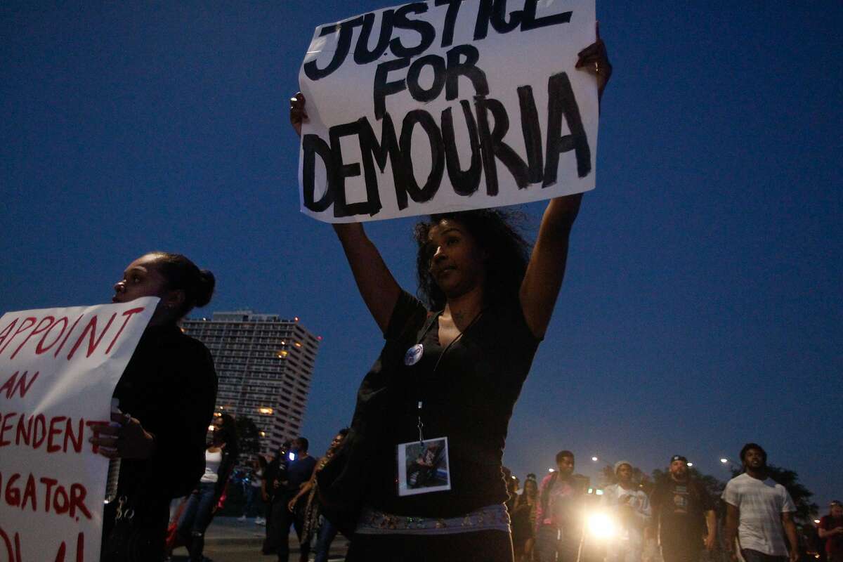 Shay Money and Irene Haines hold up signs during a march in protest of the shooting of Demouria Hogg by Oakland Police on Saturday, in Oakland, Calif., on Friday, June 12, 2015.