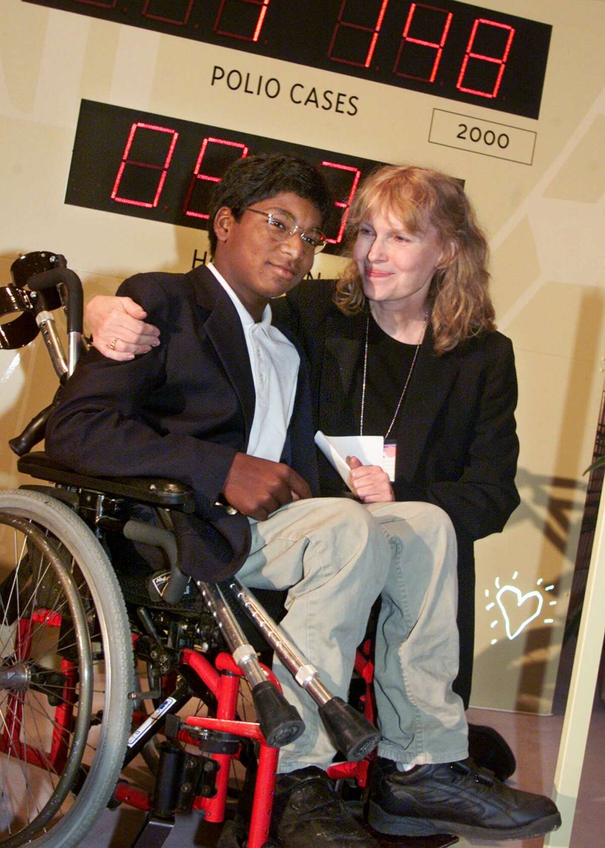 Actress Mia Farrow puts her arm around her adopted son Thaddeus as they participate in the global summit on polio eradication Wednesday, Sept. 27, 2000, at United Nations headquarters. Farrow, who suffered from the disease as a child, and her 12-year-old son who is paralyzed by it, joined U.N. Secretary General Kofi Annan in starting a clock to countdown the number of polio cases until 2005. (AP Photo/Richard Drew)