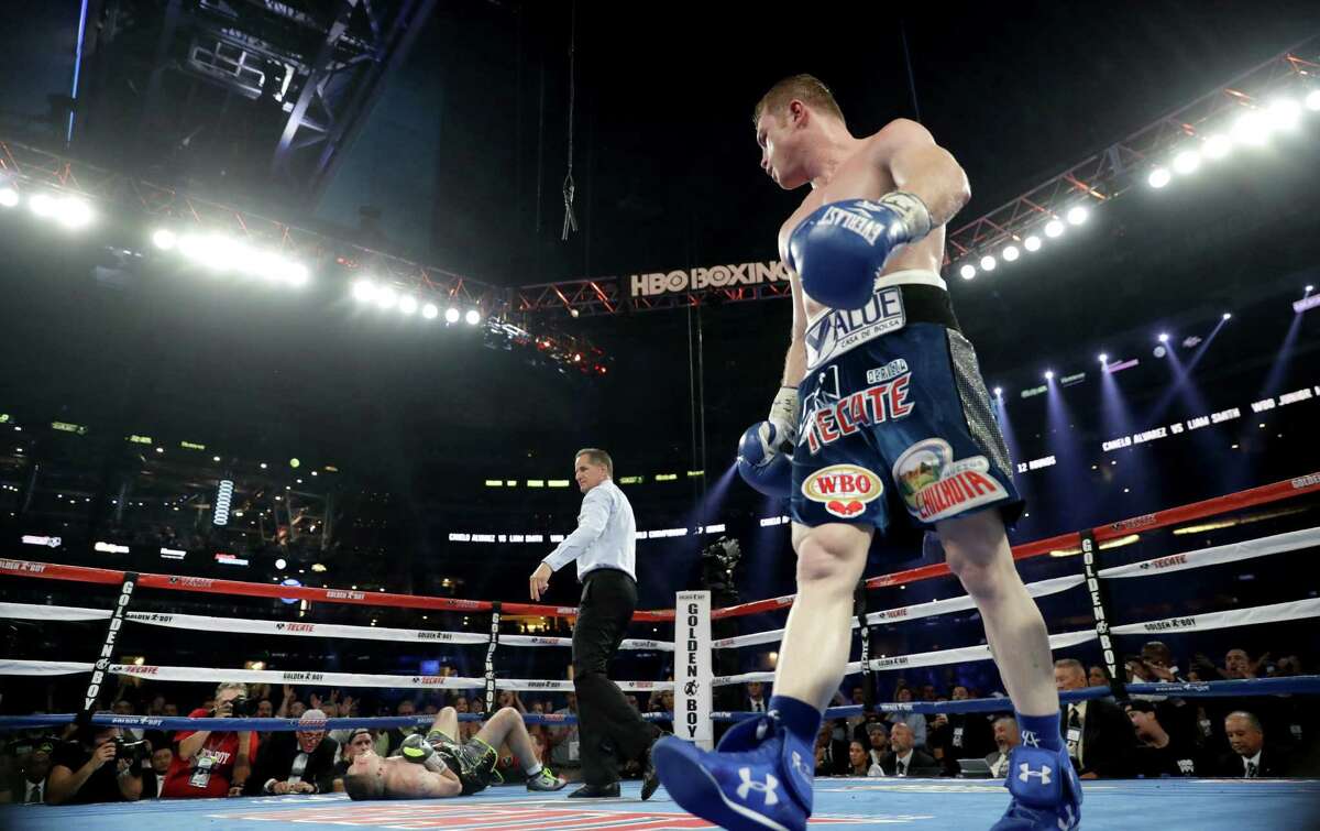 Canelo Alvarez (right) looks toward Liam Smith after knocking him down during the WBO junior middleweight world-title fight at AT&T Stadium on Sept. 17, 2016 in Arlington.